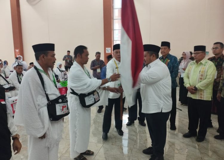 Bupati Tapsel Dolly Pasaribu (kanan) saat menyerahkan bendara merah putih kepada Kamidun Solin Bin Poceng Solin sebagai Pimpinan Kloter 23 Embarkasi Medan.(Satunusantara news/Munawar).