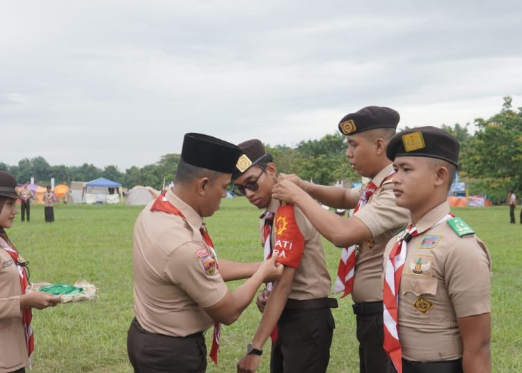 Danbrigif 7/RR, Kolonel Inf Aidil Amin (kiri) saat memasangkan tanda peserta kepada seorang Penegak, pada pembukaan  Kemah Bela Negara (KBN) Kwarda Gerakan Pramuka Sumut TA 2024. (Satunusantara news/HO-Pendam I/BB).