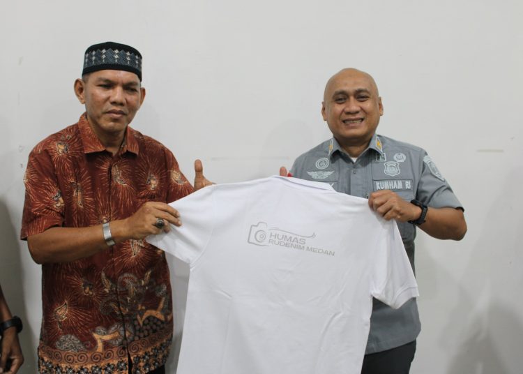 Kadiv Keimigrasian Kanwil Kemenkumham Sumut, Wely Wiguna (kanan) saat memberikan kaos dari Humas Rudenim Medan kepada perwakilan wartawan Unit Kemenkumham Sumut pada acara Refleksi Akhir Tahun 2024 Rudenim Medan.(Satunusantara 
 news/HO-Humas Rudenim Medan).