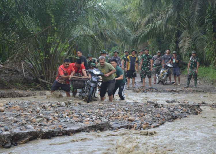 Satgas TNI TMMD ke-123, Kodim 0212/Tapsel, saat membantu warga yang menggunakan sepeda motor menyebrangi sungai di Desa Pintu Padang, sebagai wujud pengabdian kepada masyarakat.(Satunusantara news/HO-Pendim 0212/Tapsel).