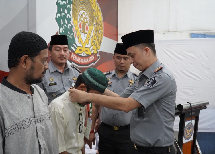 Karutan Kelas I Medan, Andi Surya (kanan) saat memasangkan tanda pengenal kepada warga binaan yang melaksanakan kegiatan Pesantren Kilat di Rutan Medan.(Satunusantara news/HO-Rutan Medan).