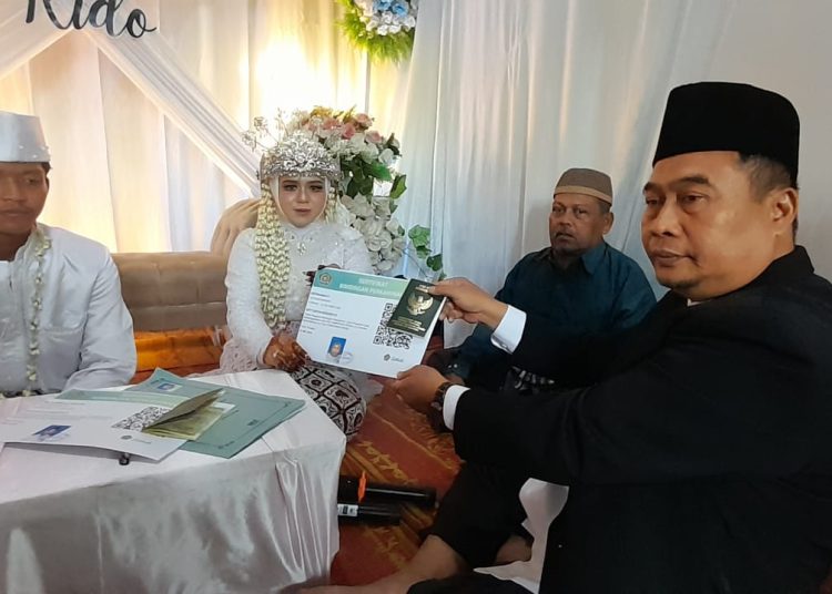 Kepala KUA Hamparan Perak Misman (kanan) saat memperlihatkan buku nikah, selesai ijab qobul, bertempat di kompleks Perumahan PT.IRA Dusun II, Desa Hamparan.(Satunusantara news/HO-Humas Kemenag Deli Serdang).