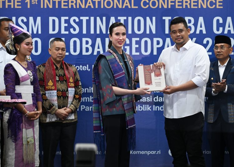Menteri Pariwisata, Widiyanti Putri Wardhana (tengah) saar menyerahkan cendramata kepada Gubernur Sumut Muhammad Bobby Afif Nasution (kanan) pada acara  Konferensi Pertama Destinasi Geowisata Kaldera Toba Unesco Global Geopark 2025, di Kabupaten Simalungun.(Satunusantara news/HO-Diskominfo Sumut).