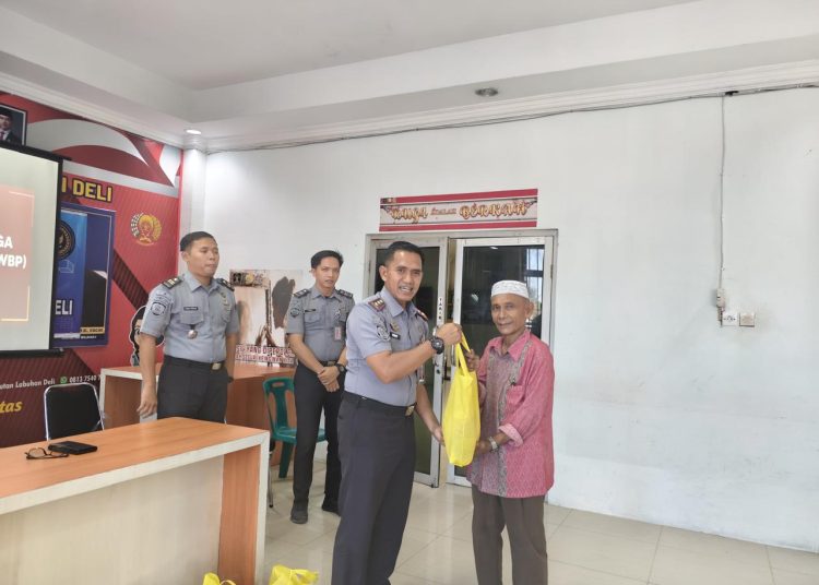 Kepala Rutan Labuhan Deli Eddy Junaedi (kiri) saat menyerahkan bantuan semabko kepada warga yang tinggal di sekitar Rutan Labuhan Deli.(Satunusantara news/HO-Rutan Labuhan Deli).