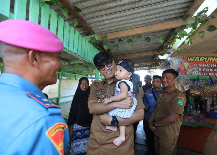 Wali kota Medan Rico Tri Putra Bayu Waas (tengah)  menggendong seorang anak saat melakukan kunjungan ke Kampung Nelayan Belawan, Kelurahan Belawan I, Kecamatan Medan Belawan, Kota Medan.(Satunusantara news/HO-Diskominfo Medan).