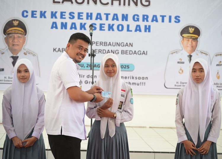 Gubernur Sumut Bobby Nasution, saat   menyerahkan kupon berobat gratis kepada siswa  di SMAN 1 Perbaungan, Kabupaten Sergai.(Satunusantara news/HO-Diskominfo Sumut).