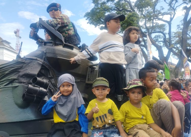 Masyarakat ikut menaiki kendaraan taktis militer pada acara Perayaan Hari HUT ke-80 TNI yang digelar di Lapangan Merdeka Medan.(Satunusantara news/Munawar).