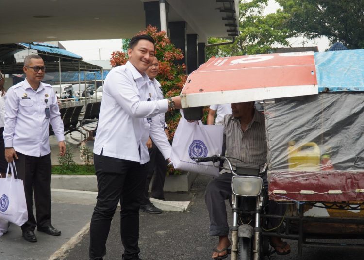 Kepala Rutan Kelas I Medan, Andi Surya, (kiri) saat memnerikan paket bantuan kepada penarik becakk.(Satunusantara news/HO-Rutan Medan).