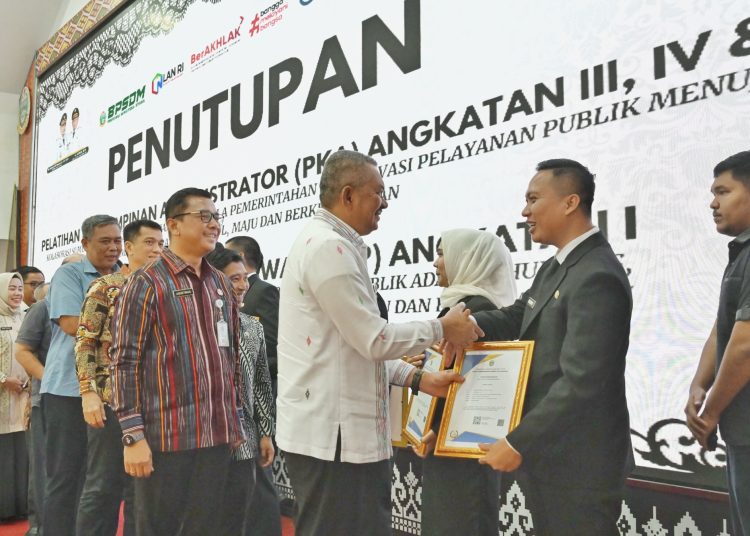 Pj Sekdaprov Sumut Sulaiman Harahap (kiri) saat menyerahkan piagam penghargaan kepada peserta PKA Angkatan III, IV, dan V serta PKP Angkatan I di Aula BPSDM Sumut.(Satunusantara news/HO-Diskominfo Sumut).