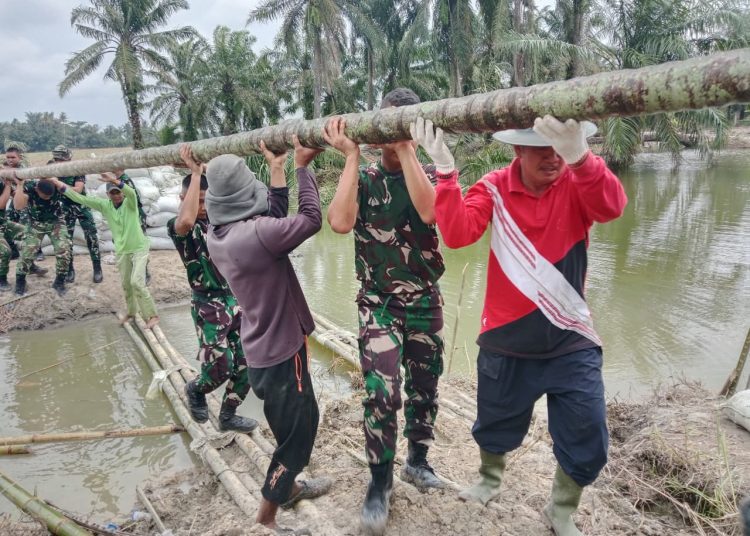 Personel Koramil  07/Stabat bersama warga Desa Stabat Lama, Kecamatan Wampu, Kabupaten Langkat, melaksanakan perbaikan tanggul yang kembali jebol akibat hujan deras.(Satunusantara news/HO-Pendam I/BB).