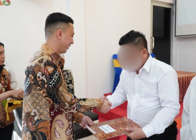 Kepala Rutan Kelas I Medan, Andi Surya (kiri) saat menyerahkan SK Remisi Khusus Natal  Tahun 2025 kepada salah seorang warga binaan di Gereja Oikoumene Imanuel Rutan Kelas I Medan.(Satunusantara news/HO-Rutan Medan)