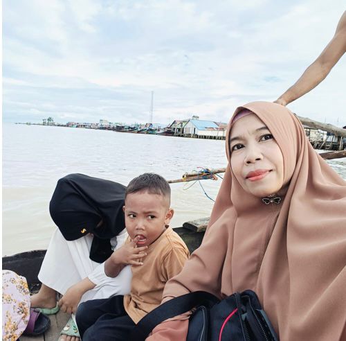 Latifah Sudarmy, Penyuluh Agama Islam KUA Kecamatan Tanjung Tiram, Kabupaten Batu Bara, saat menyeberangi laut dengan menggunakan sampan kecil menuju Desa Bandar Raahmat, demi melaksanakan Syiar Islam.(Satunusantara news/HO-Humas Kanwil Kemenag Sumut).