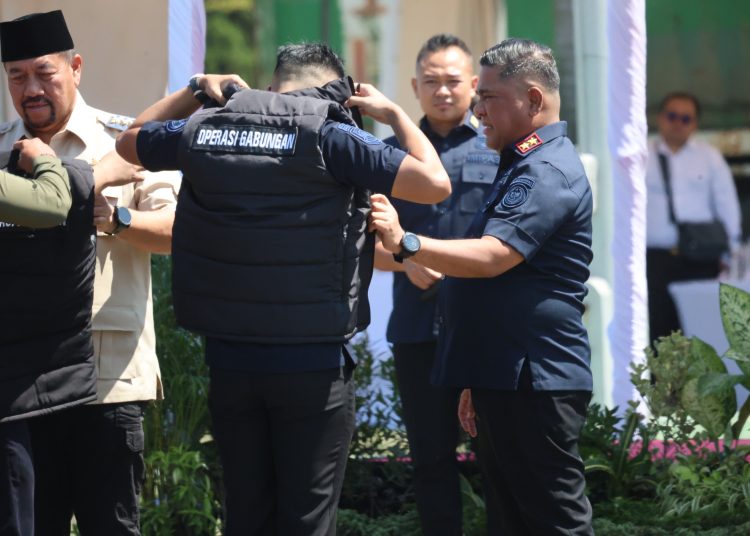 Kakanwil Ditjen Imigrasi Sumut, Dr.Parlindungan kanan) saat memsangkan rompi kepada salah seorang petugas Operasi Gabungan Laut di Lapangan PT INALUM, Kabupaten Batu Bara.(Satunusantara news/HO-Kanwil Imigrasi Sumut).